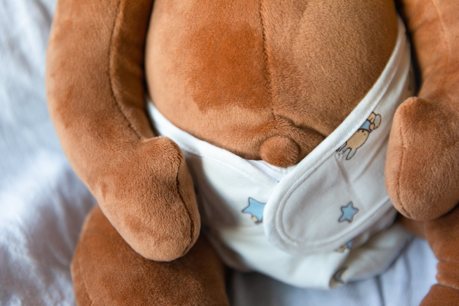 website banner featuring the belly of a brown weighted baby doll wearing a white diaper with blue stars and bunnies
